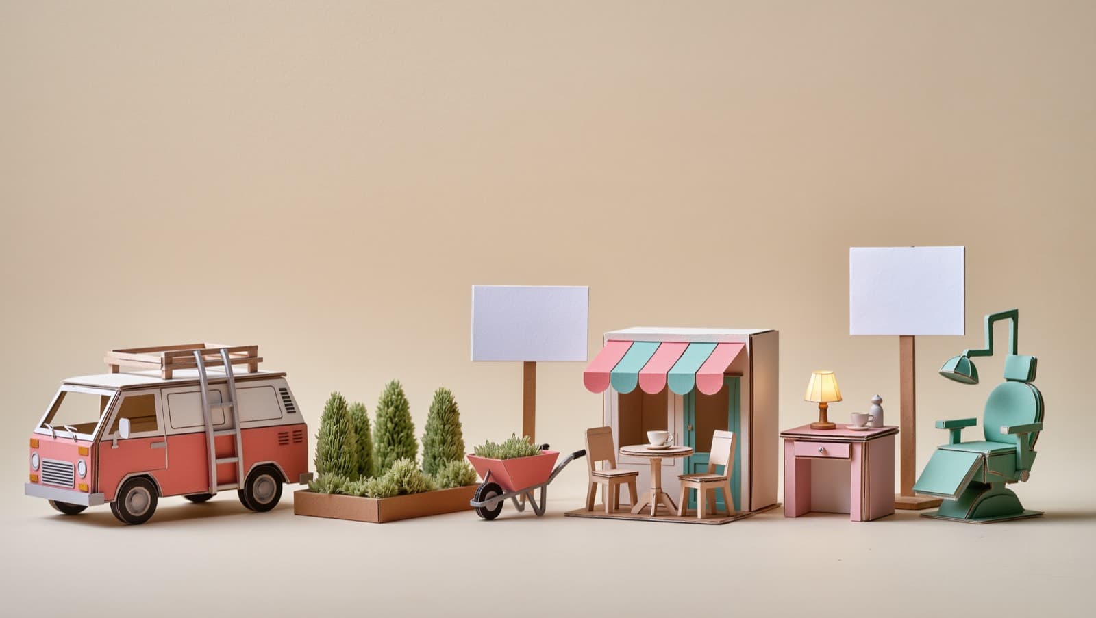 A row of miniature paper trade scenes: a camper van with a ladder, garden hedges and a wheelbarrow, a café table, a desk with a lamp, and a dentist chair